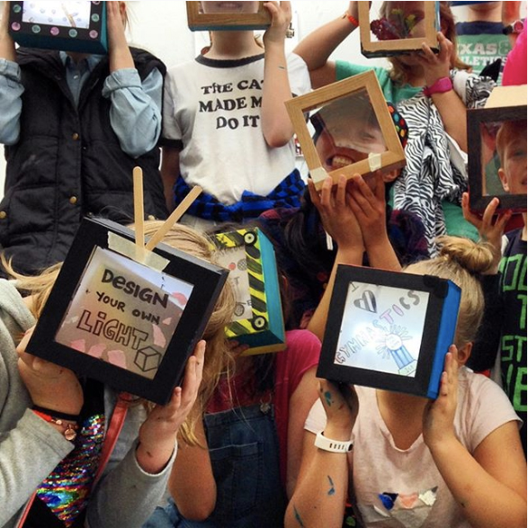 Children proudly holding up their handmade light boxes in a workshop